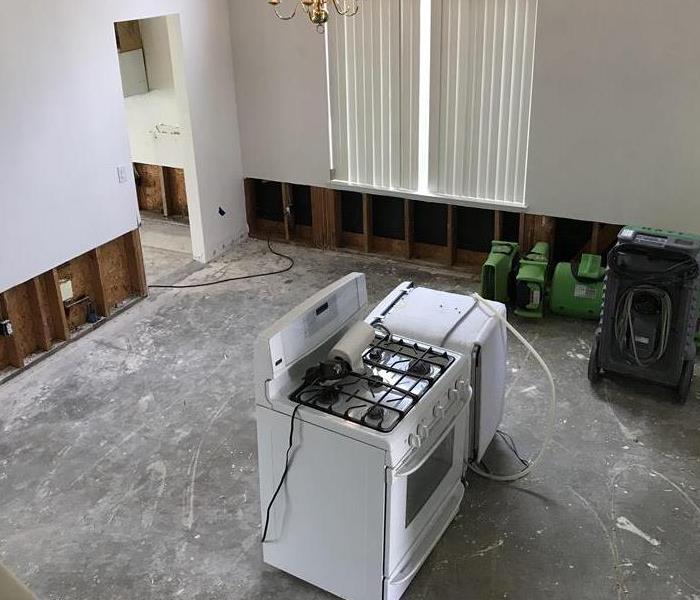 An empty living room with a lone washing machine after a water loss.