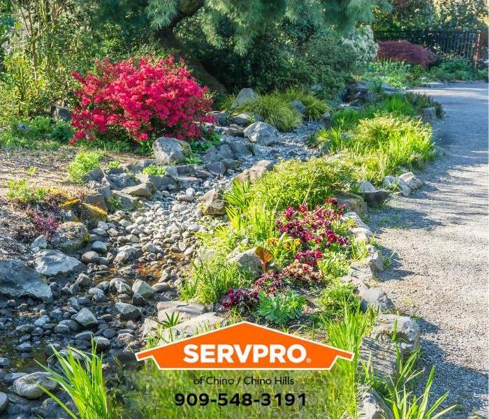 A dry creek bed runs along a driveway to direct rainwater runoff away from a property.